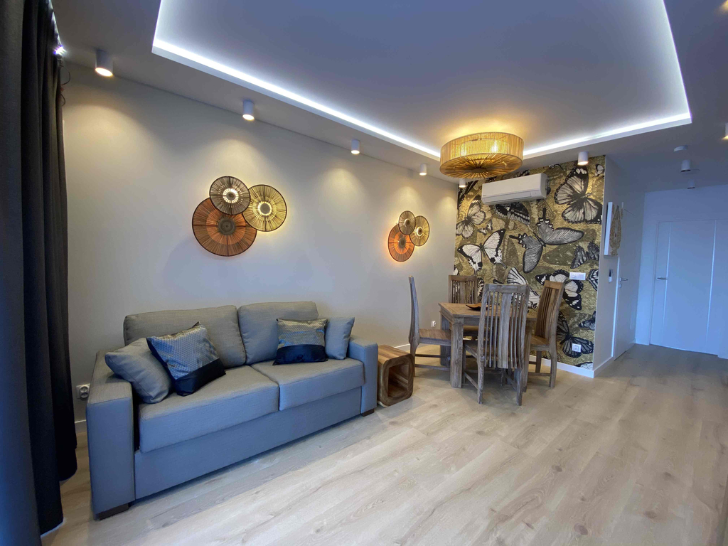 Wohn- und Essbereich der Butterfly Suite mit grauem Sofa und Schmetterlings-Akzentwand