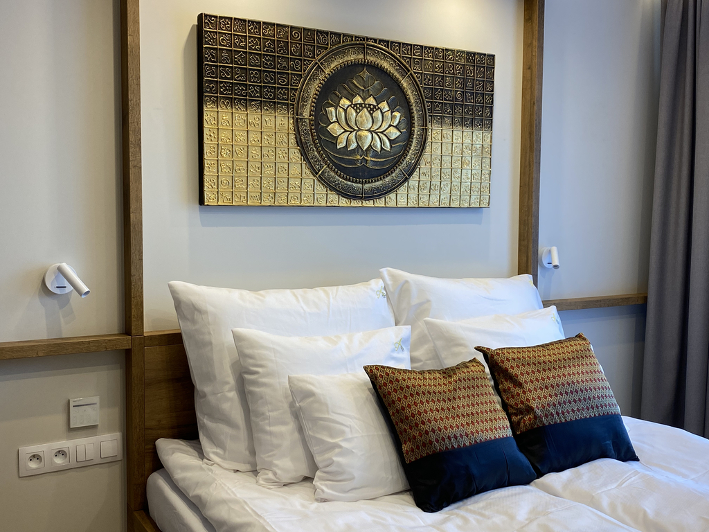 Doppelbett der Butterfly Suite mit goldener Lotus-Wandkunst und dekorativen Kissen