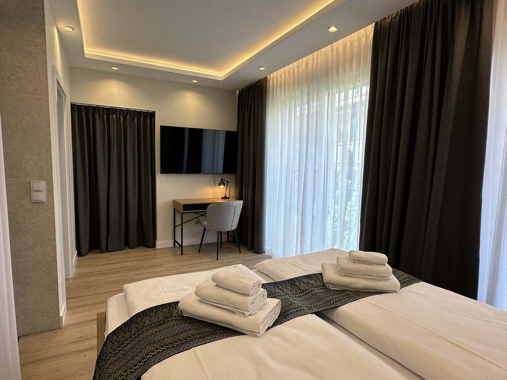 Schlafzimmer der Camilla Suite mit Doppelbett, Wand-TV und Arbeitsplatz am bodentiefen Fenster