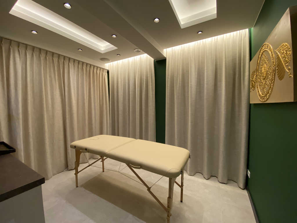 Tree Room im ARALIYA Krakau mit Massageliege vor grüner Wand und goldenem Wandrelief