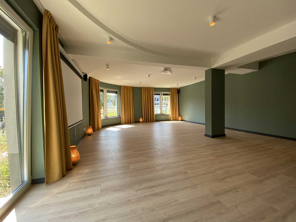 Studioraum im ARALIYA Krakau mit Projektionsleinwand, gelben Vorhängen und Holzboden