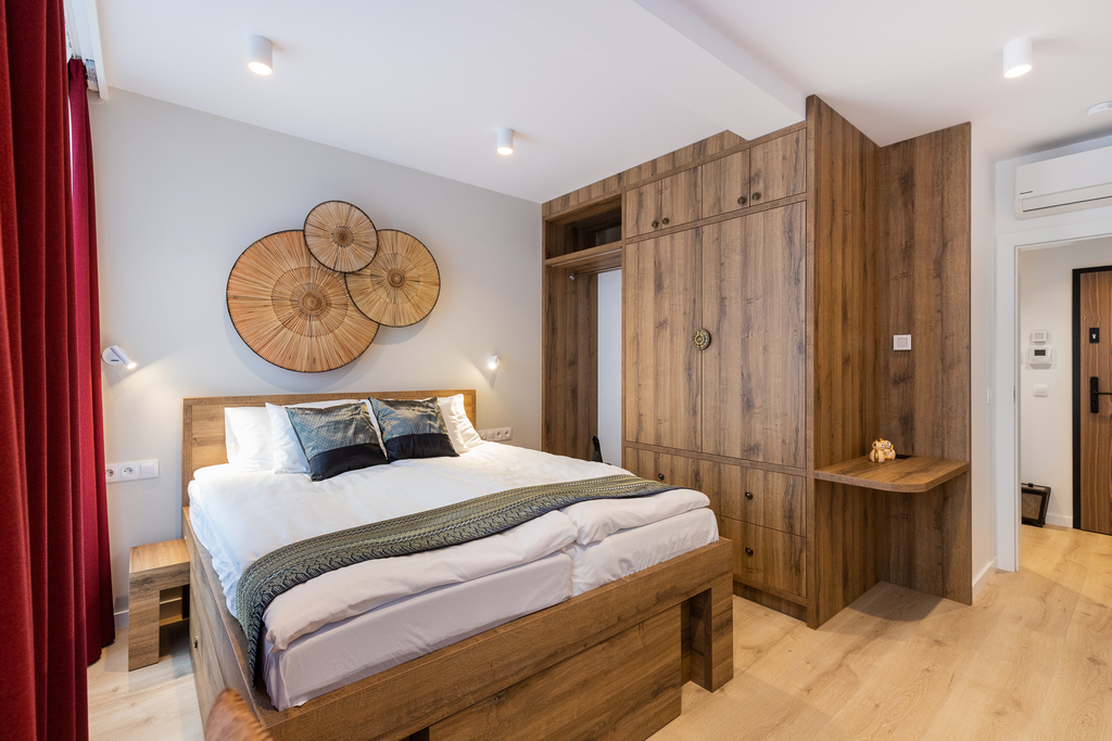 Schlafzimmer der Queen Suite mit Doppelbett, großem Holz-Kleiderschrank und dekorativen Wandfächern