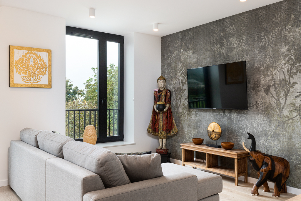 Sitzbereich der King Suite mit Sofa, Wand-TV und thailändischer Buddha-Statue