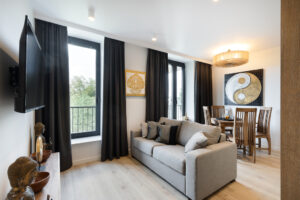 Wohnbereich der Elephant Suite mit Sofa, Wand-TV, Essplatz und Balkonfenster