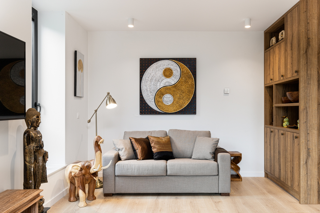Wohnbereich der Cosmea Suite mit grauem Sofa, goldenem Yin-Yang-Bild und Buddha-Figur